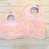 cute lilttle baby girl bib of light rosy pink with a lovely white design and backed with thick white terry