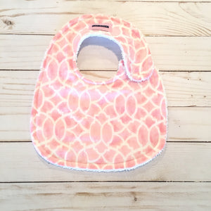 cute lilttle baby girl bib of light rosy pink with a lovely white design and backed with thick white terry